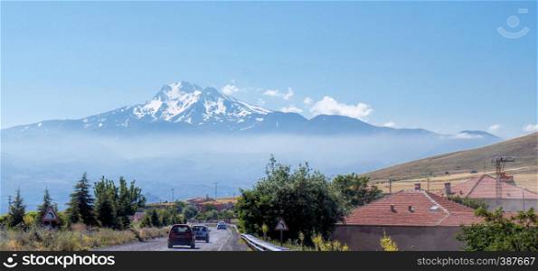 Volcano Erciyes from a distance with a fog bank underneath the summit, Anatolia, Turkey, from the driving car