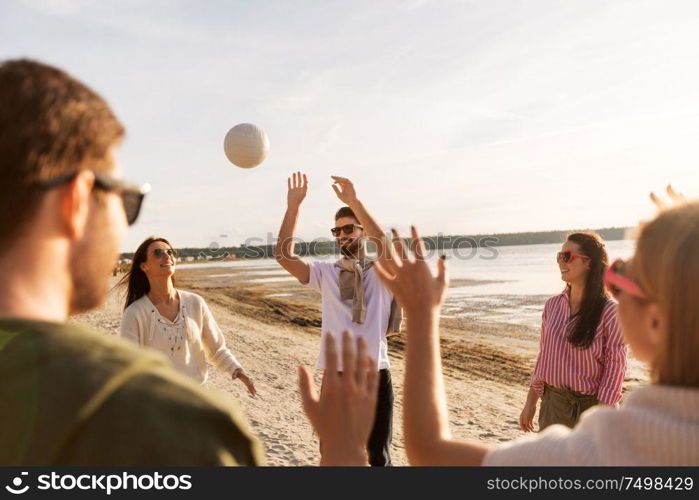 volleyball, leisure games and people concept - happy friends playing with ball on beach in summer. friends playing volleyball on beach in summer