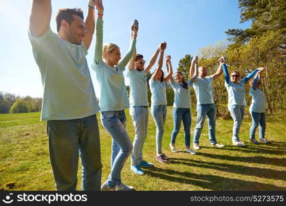 volunteering, charity and people concept - group of happy volunteers holding hands outdoors. group of happy volunteers holding hands outdoors