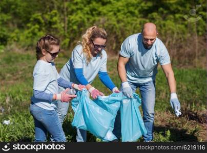volunteering, charity, cleaning, people and ecology concept - group of happy family volunteers with garbage bags cleaning area in park