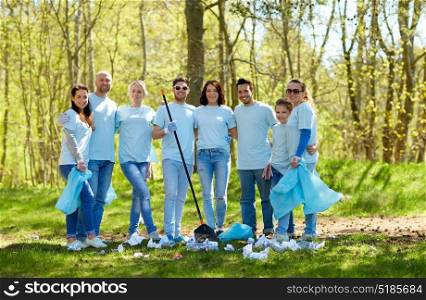 volunteering, charity, cleaning, people and ecology concept - group of happy volunteers with garbage bags and rake in park. group of volunteers with garbage bags in park