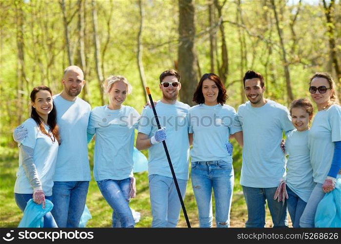 volunteering, charity, cleaning, people and ecology concept - group of happy volunteers with garbage bags and rake in park. group of volunteers with garbage bags in park