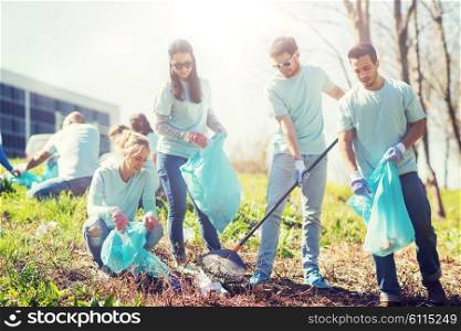 volunteering, charity, cleaning, people and ecology concept - group of happy volunteers with garbage bags cleaning area in park. volunteers with garbage bags cleaning park area. volunteers with garbage bags cleaning park area