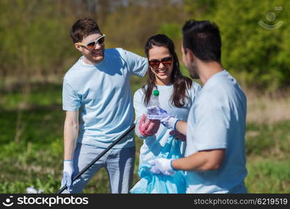 volunteering, charity, cleaning, people and ecology concept - group of happy volunteers with garbage bags cleaning area in park