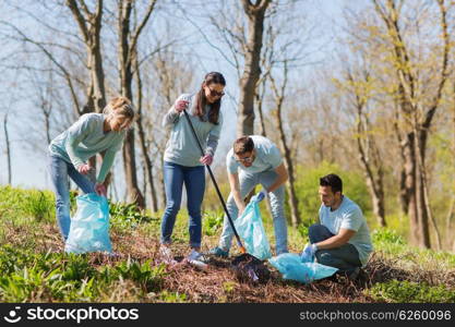 volunteering, charity, cleaning, people and ecology concept - group of happy volunteers with garbage bags cleaning area in park