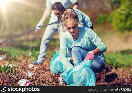 volunteering, charity, cleaning, people and ecology concept - group of happy volunteers with garbage bags cleaning area in park. volunteers with garbage bags cleaning park area