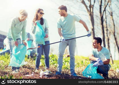 volunteering, charity, cleaning, people and ecology concept - group of happy volunteers with garbage bags cleaning area in park. volunteers with garbage bags cleaning park area. volunteers with garbage bags cleaning park area