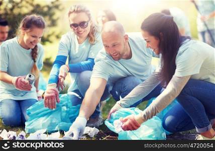 volunteering, charity, people and ecology concept - group of happy volunteers with garbage bags cleaning area in park. volunteers with garbage bags cleaning park area. volunteers with garbage bags cleaning park area