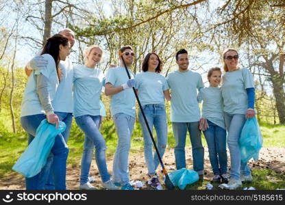 volunteering, charity, people and ecology concept - group of happy volunteers with garbage bags and rake cleaning area in park. volunteers with garbage bags cleaning park area