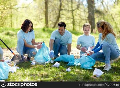 volunteering, charity, people and ecology concept - group of happy volunteers with garbage bags cleaning area in park. volunteers with garbage bags cleaning park area