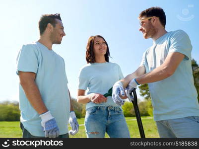 volunteering, charity, people and ecology concept - group of happy volunteers with garden tools in park. group of volunteers with garden tools in park