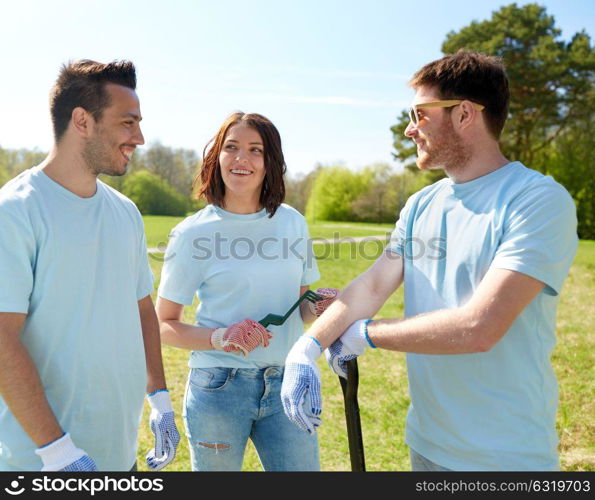 volunteering, charity, people and ecology concept - group of happy volunteers with garden tools in park. group of volunteers with garden tools in park