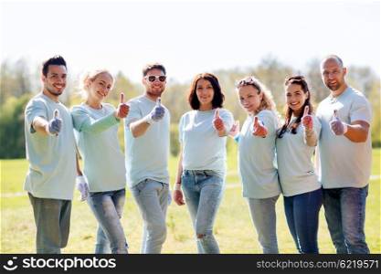 volunteering, charity, people, gesture and ecology concept - group of happy volunteers showing thumbs up in park