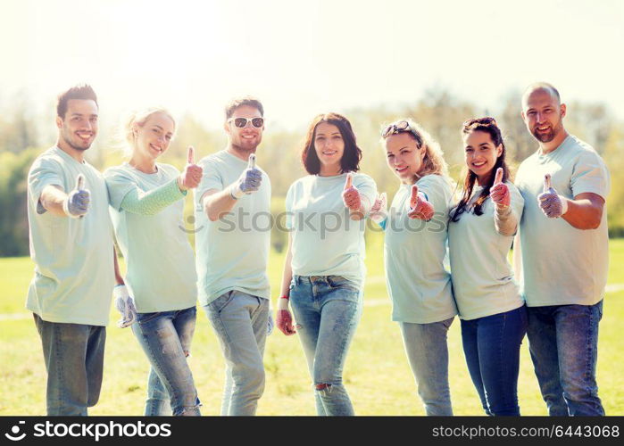 volunteering, charity, people, gesture and ecology concept - group of happy volunteers showing thumbs up in park. group of volunteers showing thumbs up in park