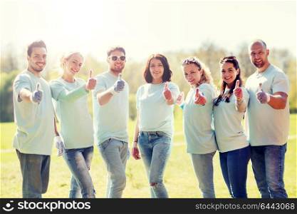 volunteering, charity, people, gesture and ecology concept - group of happy volunteers showing thumbs up in park. group of volunteers showing thumbs up in park