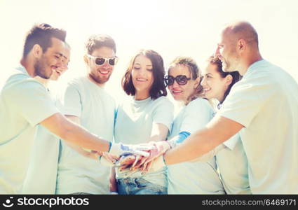 volunteering, charity, people, gesture and ecology concept - group of happy volunteers putting hands on top in park. group of volunteers putting hands on top in park