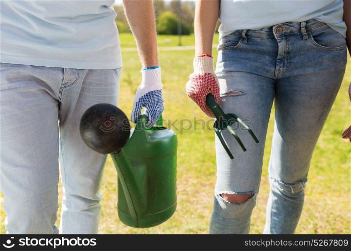 volunteering, people and gardening concept - couple of volunteers with watering can and weeding rake. volunteers with watering can and weeding rake