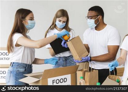 volunteers with gloves medical masks preparing box with food donation