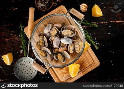 Vongole in a colander on a cutting board. On a rustic dark background. High quality photo. Vongole in a colander on a cutting board.