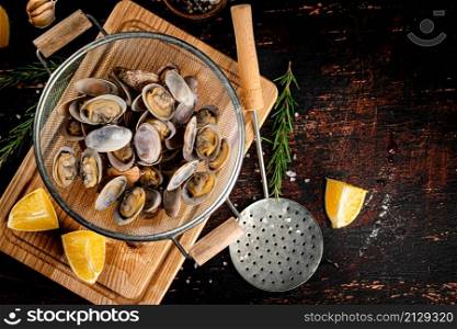 Vongole in a colander on a cutting board. On a rustic dark background. High quality photo. Vongole in a colander on a cutting board.