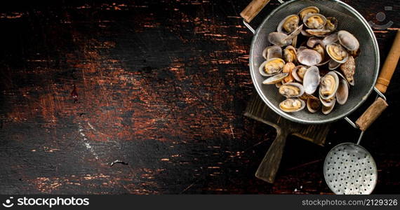 Vongole in a colander on a cutting board. On a rustic dark background. High quality photo. Vongole in a colander on a cutting board.