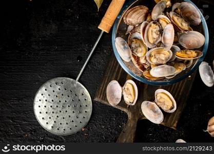 Vongole in a glass bowl on a cutting board. On a black background. High quality photo. Vongole in a glass bowl on a cutting board.