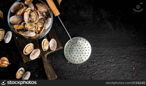 Vongole in a glass bowl on a cutting board. On a black background. High quality photo. Vongole in a glass bowl on a cutting board.