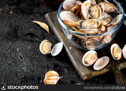 Vongole in a glass bowl on a cutting board. On a black background. High quality photo. Vongole in a glass bowl on a cutting board.