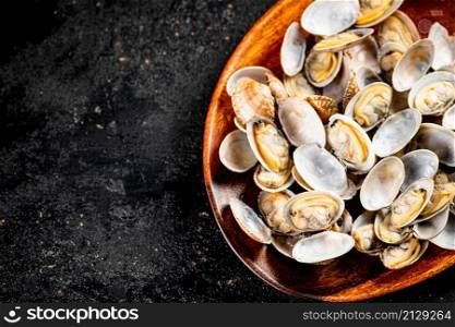 Vongole in a plate on the table. On a black background. High quality photo. Vongole in a plate on the table.