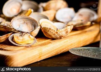 Vongole on a wooden cutting board. Against a dark background. High quality photo. Vongole on a wooden cutting board.