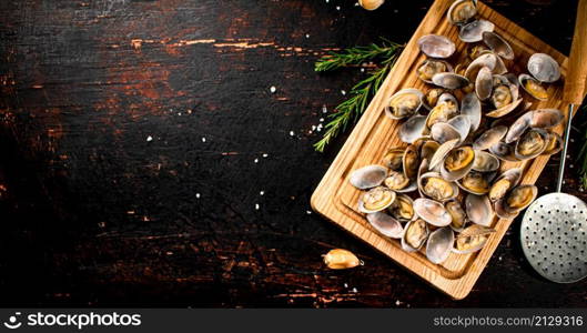 Vongole on a wooden cutting board. Against a dark background. High quality photo. Vongole on a wooden cutting board.