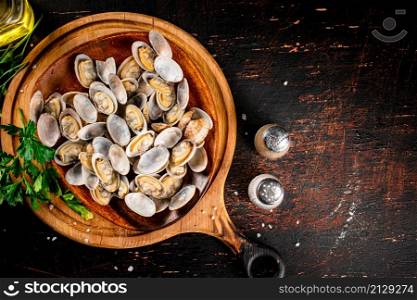 Vongole on a wooden plate with parsley. On a rustic dark background. High quality photo. Vongole on a wooden plate with parsley.