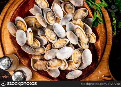 Vongole on a wooden plate with parsley. On a rustic dark background. High quality photo. Vongole on a wooden plate with parsley.