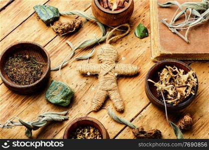 Voodoo doll, magical herbs and witchcraft attributes on an old table. Magic voodoo doll for ritual