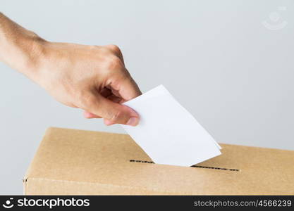 voting, civil rights and people concept - male hand putting his vote into ballot box on election