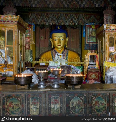 Votive candles burning in front of Buddha statue in Drepung Monastery, Lhasa, Tibet, China