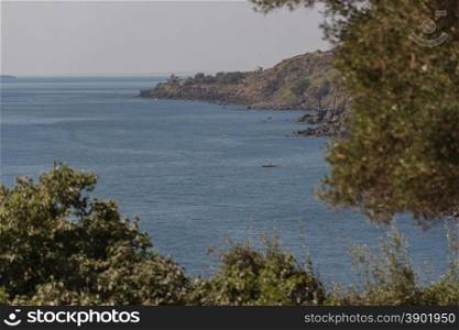 Vulcanic coast in sicily with trees and little boat