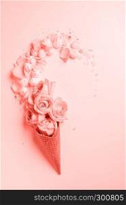 Waffle cone with composition of flowers and meringues in a color of the year 2019 Living Coral Pantone on a background same colors. Flat lay. Copy space.. Waffle cone with flowers and sweets on a color background of the year 2019 Living Coral Pantone. Top view. Place for text.