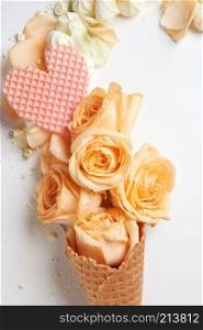 Waffle cone with composition of flowers and waffle heart on white background. Waffle cone with composition of flowers