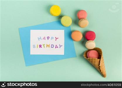 waffle cone with macaroons near happy birthday card mint green backdrop