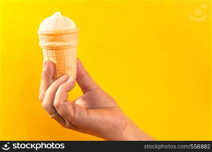 waffle cup with ice cream in hand on yellow background