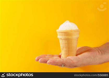 waffle cup with ice cream in hand on yellow background