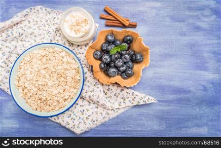 Waffle with blueberries and mint leaf. Yogurt with cinnamon and bowl of oatmeal on rustic textured background. Top view with copy space.