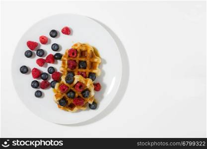 Waffles with berries and maple syrup seen from above. Waffles with berries and maple syrup