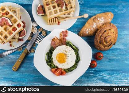 waffles with fig baked pastries egg fried egg white plates blue textured backdrop