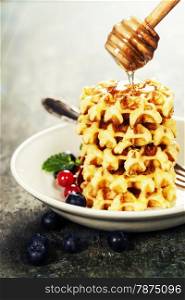 Waffles with honey on wooden table