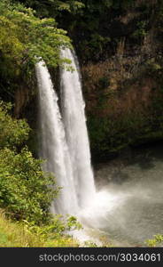 Wailua Falls in Hawaiian island of Kauai. Sun illuminates the twin falls of Wailua waterfall on Hawaiian island of Kauai. Wailua Falls in Hawaiian island of Kauai