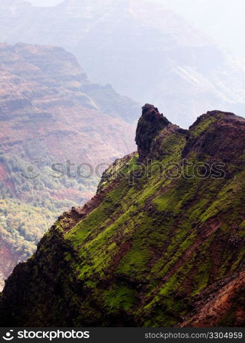 Waimea Canyon in Kauai, Hawaii with the early morning sun shining up the valley behind the rocks