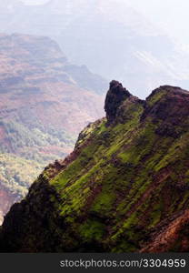 Waimea Canyon in Kauai, Hawaii with the early morning sun shining up the valley behind the rocks