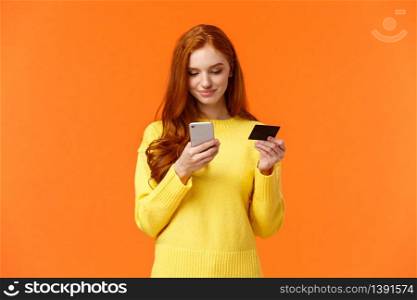 Waist-up portrait carefree modern young girl making online purchase, shopping internet using mobile application, insert credit card info smartphone, smiling, order something, orange background.. Waist-up portrait carefree modern young girl making online purchase, shopping internet using mobile application, insert credit card info smartphone, smiling, order something, orange background